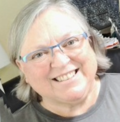 Image showing Joanne Lakomski of Human Resourceress, wearing a grey t shirt, glasses and side parted hair, smiling towards the camera.