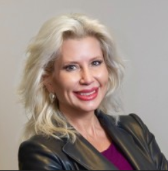 Image showing Alicia Samolis of Patridge Snow Hahn, with long blond hair, wearing a jacket, smiling towards the camera.